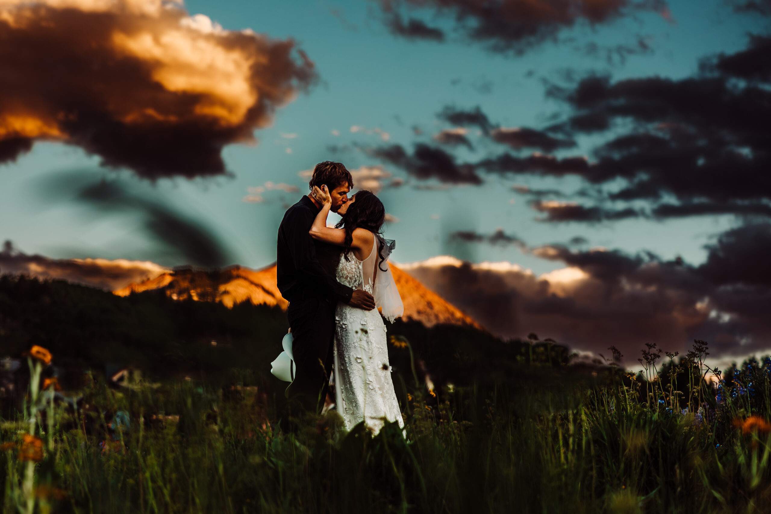 Colorado Elopement Photographer | Pictured is in elopement at a golf course outside of Beaver Creek, Colorado. The couple and their immediate families are all standing on the golf course, which overlooks a huge valley. It was a windy day so the bride's veil was flailing about. At this moment, the bride's sister is adjusting the bride's veil. 